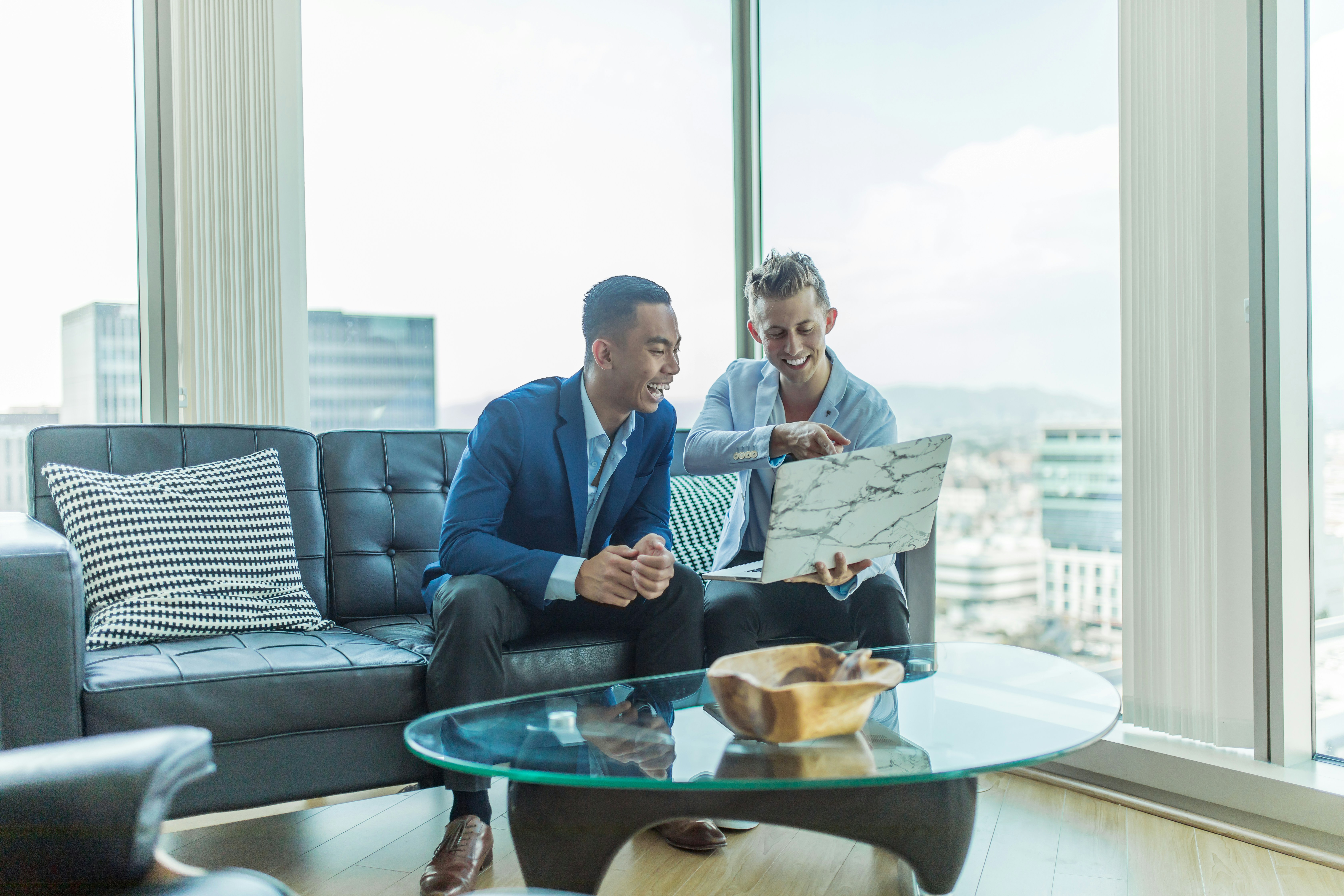 Two men sitting in front of a laptop